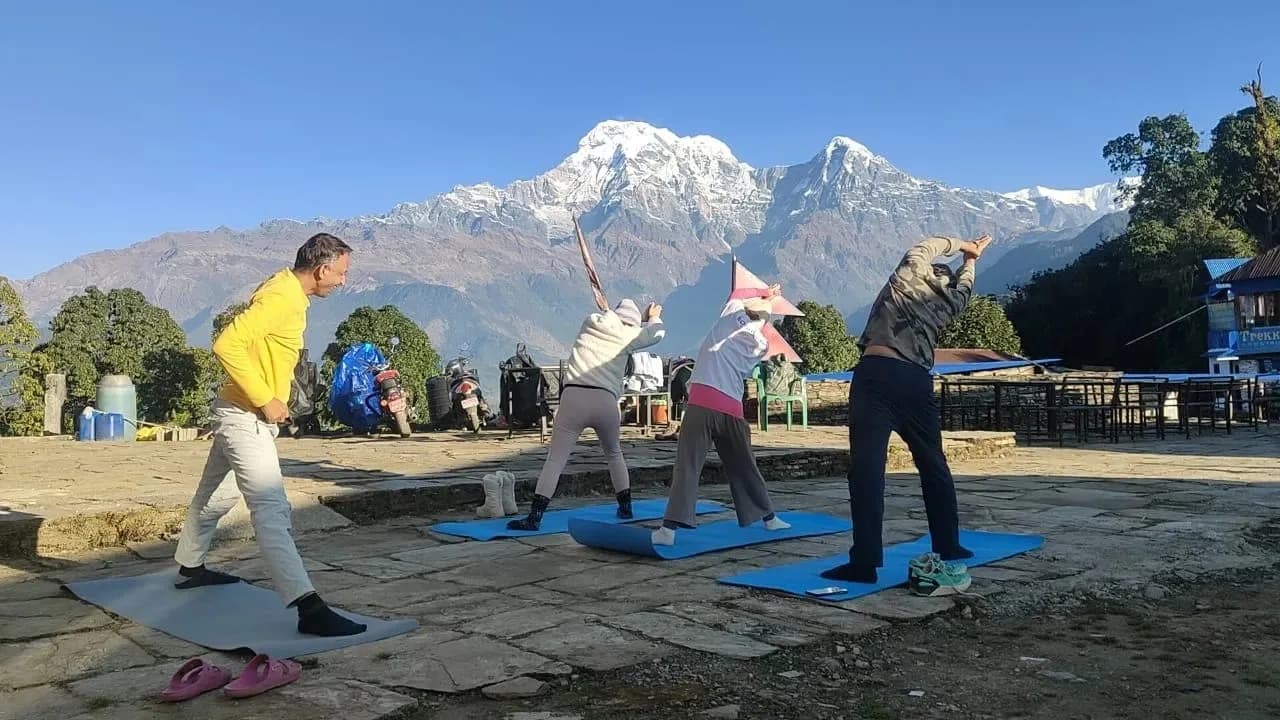 Bodhidham retreat guests practising yoga outdoors with the Annapurna range behind them